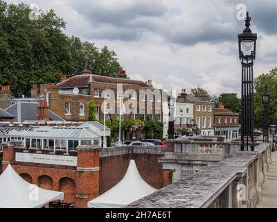 MOLESEY, SURREY, Großbritannien - 09. JULI 2021: Blick entlang der Hampton Court Brücke in Richtung Mitre Hotel und Mute Swan Pub in East Molesey Stockfoto