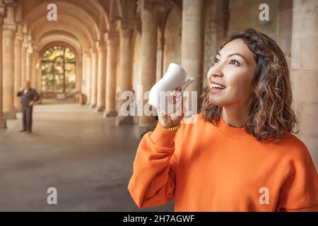 Glückliche asiatische Frau trinkt gesundes Mineralwasser in einem der berühmten europäischen medizinischen und therapeutischen Resorts Stockfoto
