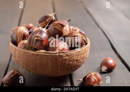 Nahaufnahme von leckeren süßen Kastanien in einer Schüssel auf einem Holztisch Stockfoto