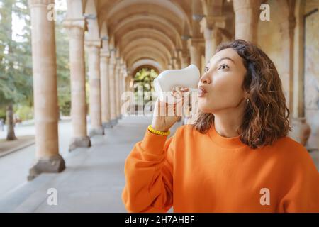 Glückliche asiatische Frau trinkt gesundes Mineralwasser in einem der berühmten europäischen medizinischen und therapeutischen Resorts Stockfoto