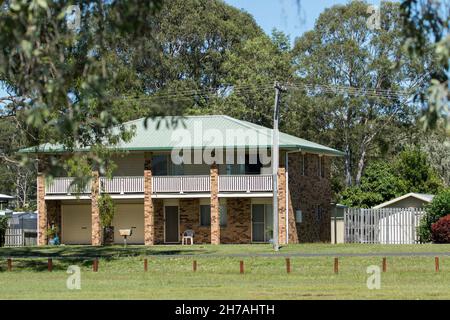 Modernes doppelstöckiges Backsteinhaus, Ferienhaus oder Investment-Anwesen, in einer Küstenstadt in Australien mit Rasen und neben einem Wald mit hohen Bäumen Stockfoto