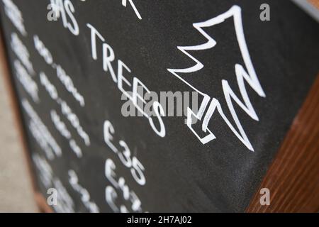 Von Hand gezeichneter Weihnachtsbaum mit Kreide auf einem Hintergrund aus schwarzen Brettschauchen und Pfundpreisen. Weihnachtsbaum Verkauf. Stockfoto