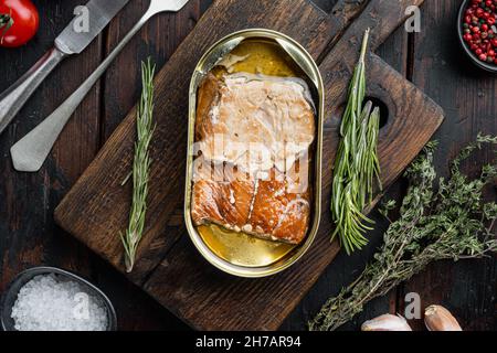 Wild Pink Salmon Räucherfischset in Dosen, auf Holzschneidebrett, auf altem dunklen Holztisch mit Kräutern und Zutaten, Draufsicht flach Stockfoto