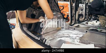 Prozess der Installation von Schalldämmmaterial auf der Innenseite des Autos. Automatische Schalldämmung. Stockfoto