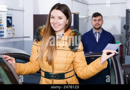 Die junge Frau ist zufrieden mit dem Reifenwechsel ihres Autos im Winter Stockfoto
