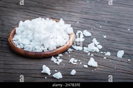 Meersalz in einer Schüssel auf einem hölzernen Hintergrund. Mineral auf dem Tisch verstreut Stockfoto