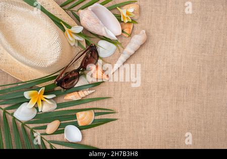 Hut und Sonnenbrille in der marinen Dekoration. Muscheln und Blumen schmücken einen Strohhut Stockfoto