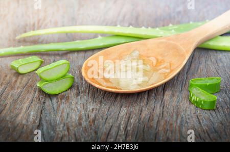 Frische Blätter und Stücke Aloe Vera Gel im Löffel auf der Holzoberfläche Stockfoto