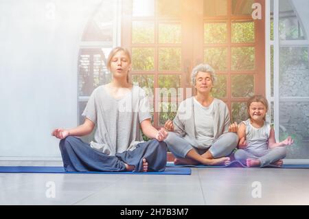 Senioren mit Teenagern und Enkelkindern, die zu Hause Yoga machen Stockfoto