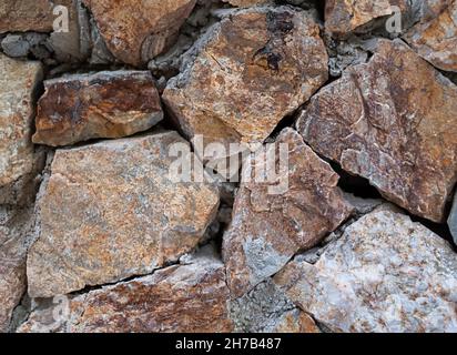 Textur von Steinen auf dem Boden grau und orange Kieselsteine. Stein Hintergrund Stockfoto