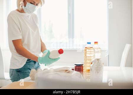 Quarantäne - zu Hause bleiben. Seitenansicht einer Frau, die Essen für die Spende vorbereitet Stockfoto