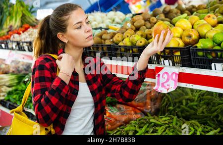 Porträt einer jungen Kundin im Laden in der Nähe der Theke mit einem Apfel Stockfoto