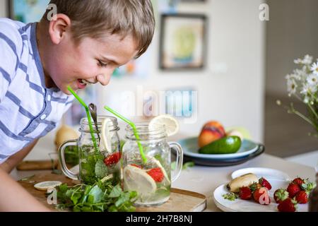 Zwei lachende kleine Jungen trinken erfrischenden Vitamin Sommer Cocktail aus Glas verwenden Stroh Spaß haben Stockfoto