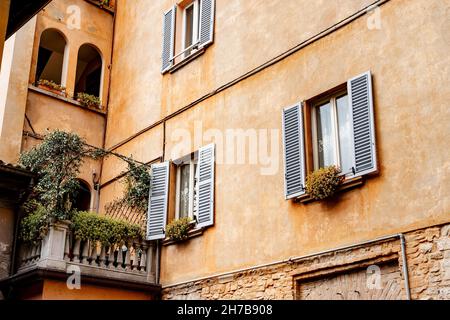 Altes gemütliches Haus mit Blumen auf dem Balkon und Fenstern. Bergamo, Italien Stockfoto