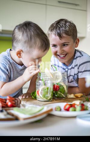 Zwei lachende kleine Jungen trinken erfrischenden Vitamin Sommer Cocktail aus Glas verwenden Stroh Spaß haben Stockfoto