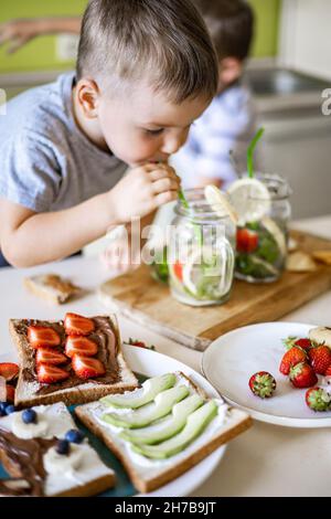 Zwei lachende kleine Jungen trinken erfrischenden Vitamin Sommer Cocktail aus Glas verwenden Stroh Spaß haben Stockfoto