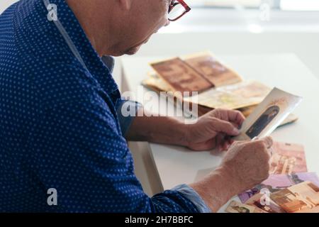 Älterer Mann schaut sich alte Fotoalbumthemen von Erinnerungen an Stockfoto