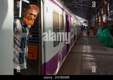 Ein muslimischer Mann mit hennafarbenem Bart steht am Eingang eines Bogeys eines Vorstadtzugs am Chhatrapati Shivaji Maharaj Terminus in Mumbai, Indien Stockfoto