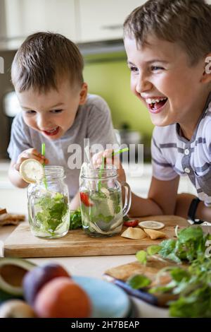 Zwei lachende kleine Jungen trinken erfrischenden Vitamin Sommer Cocktail aus Glas verwenden Stroh Spaß haben Stockfoto