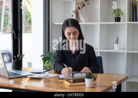 Konzentrierte asiatische Geschäftsfrau, die mit Datenchart-Dokumenten und Laptop-Computer arbeitet, Business-Finanzkonzept Stockfoto