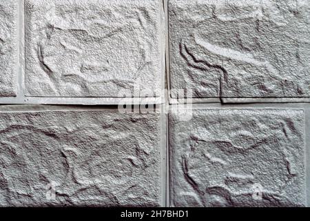 Die Tapete beginnt sich abzulösen. Die Tapete aus alten weißen Ziegeln schälte sich von der Wand im Raum, weil es feucht war oder sich nicht gut klebte. Reparieren Sie A Stockfoto