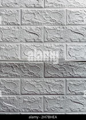 Die Tapete beginnt sich abzulösen. Die Tapete aus alten weißen Ziegeln schälte sich von der Wand im Raum, weil es feucht war oder sich nicht gut klebte. Reparieren Sie A Stockfoto