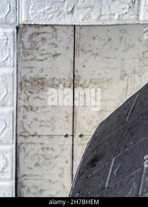 Die Tapete beginnt sich abzulösen. Die Tapete aus alten weißen Ziegeln schälte sich von der Wand im Raum, weil es feucht war oder sich nicht gut klebte. Reparieren Sie A Stockfoto