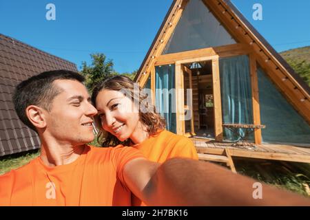 Ein verliebtes Paar umarmt sich vor dem Hintergrund eines kleinen Holzhauses in den Bergen Stockfoto