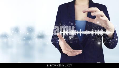 Konzept der Musik mit Ihnen, Software für die Aufnahme verwendet. Zwei Hand halten virtuelle holographische Soundtrack, Welle-Symbol mit Licht verschwommen Hintergrund. Stockfoto