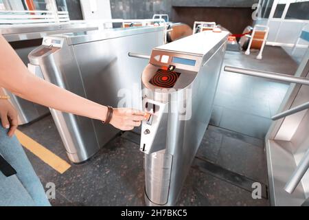 Ein Ticket-Token in der Hand des Passagiers, bevor er durch die Drehkreuze in der U-Bahn fährt Stockfoto