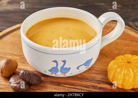 Samtige Kürbis- und Kastaniensuppe auf Holzständer Stockfoto