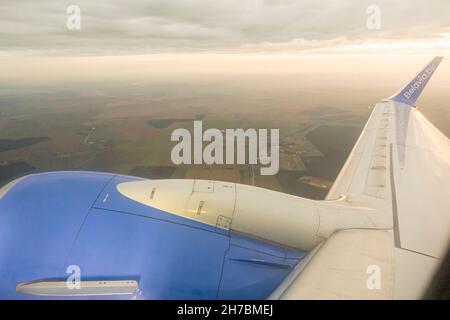 Jet-Triebwerk und Flügel eines Boeing 737-800-Flugzeugs von Belavia, das am Sonnenuntergang über Weißrussland fliegt Stockfoto