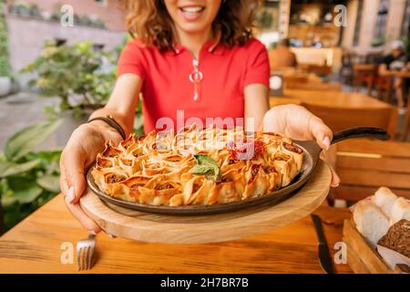 Frau, die im Restaurant offene Manti oder Knödel auf einer Bratpfanne isst. Traditionelle Küche orientalischer und turkischer Menschen Stockfoto