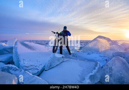 Mann mit fetten Fahrrad auf dem gefrorenen See Kapchagay bei Sonnenuntergang in Kasachstan Stockfoto