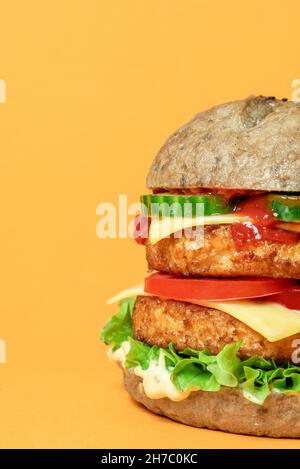 Nahaufnahme mit einem hausgemachten veganen Burger. Köstlicher Cheeseburger aus veganen Zutaten, Fleisch auf pflanzlicher Basis, Cashewkäse, Roggenbrotbrötchen und Vegeta Stockfoto