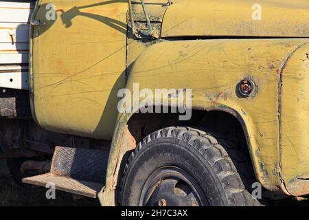 Ein altes verlassene Auto. Rostige und abgenutzte Kabine eines alten Lastwagens. Fragment der Fahrzeugfront und des Rades. Sterbender LKW oder LKW Stockfoto