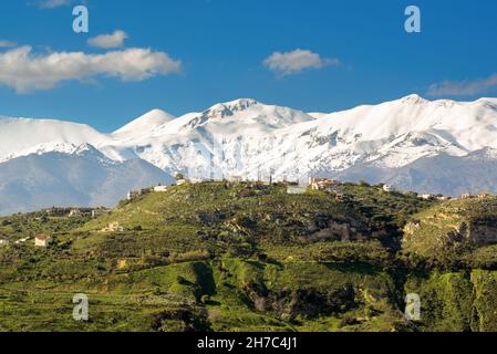 Berglandschaft mit Dorf gegen schneebedeckte Gipfel Stockfoto