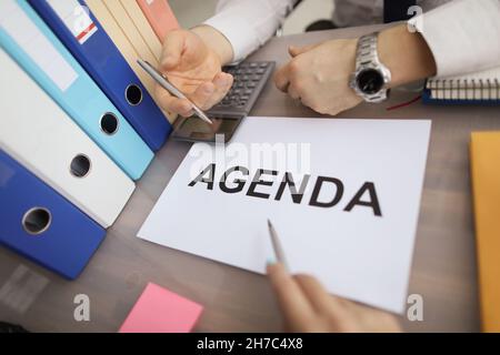 Kollegen sitzen am Arbeitsplatz mit einer Textagenda auf einem White Paper Stockfoto