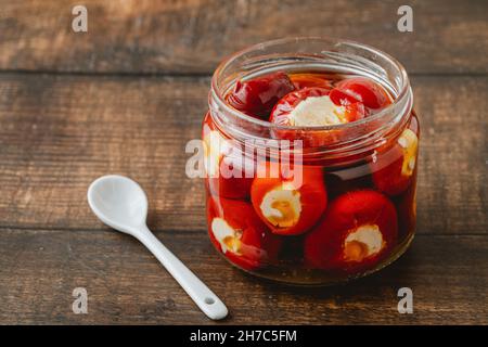 Gefüllte Kirschpaprika mit Ricotta-Käsefüllung im Glas auf Holzboden Stockfoto