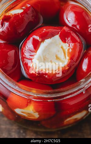 Gefüllte Kirschpaprika mit Ricotta-Käsefüllung im Glas auf Holzboden Stockfoto