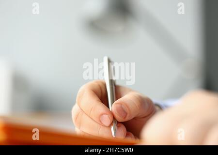 Professioneller Geschäftsmann, der seine Idee in einem Notizbuch mit silbernem Stift schreibt Stockfoto
