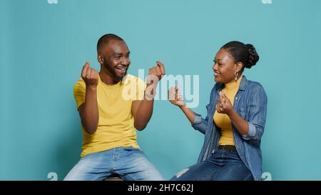 Menschen, die Körpersprache verwenden, um Geldgesten mit den Händen im Studio zu tun. Mann und Frau reiben sich die Finger und fordern Barzahlung und Gewinn. Gieriges Paar tut Belohnung Zahlung Symbol. Stockfoto