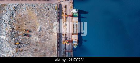 Abfallverladung auf dem Hafenfrachtschiff Transporte von Müll für die Recycling-Fabrik. Konzept Kunststoff Verschmutzung Umwelt, Luftaufnahme von oben. Stockfoto