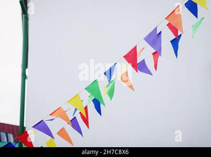 Mehrfarbige dreieckige Fahnen hängen im Freien am Himmel Stockfoto
