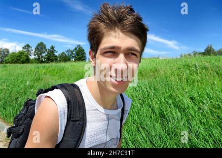 Junger Mann mit Knapsack geht im Sommerfeld Stockfoto