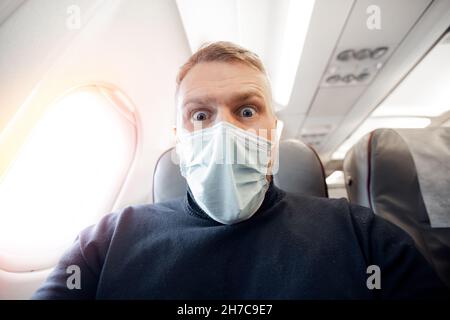 Angst vor dem Fliegen im Flugzeug und Höhe Tourist Mann in sichere medizinische Maske. Konzept Aerophobie oder Aviophobie. Stockfoto