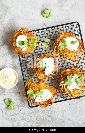 Hash-braune Kartoffel mit weißer Sauce und Koriander. Kartoffelpfannkuchen. Leckere Gemüsefritter. Kartoffelpasteten oder Kartoffelrösti. Knusprig gehackter gebräunter P Stockfoto