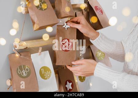 Hängender Weihnachtsadventkalender an der Wand. Handgefertigte Basteltaschen mit Geschenken und Aufgaben für Kinder. Countdown für Heiligabend, warten auf Wunder Stockfoto