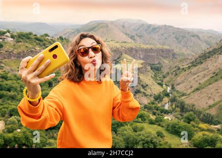 Reisegloggerin, die Selfie-Fotos auf einem Hintergrund eines wunderschönen Flusstals und der Rockformation „Symphony of Stones“ in Garni, Armenien, macht Stockfoto