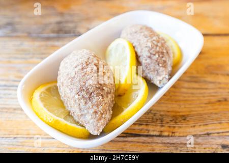 Kufta oder gehackte putenschnitzel mit Zitrone auf einem Teller ist ein traditionelles Gericht in den türkischen und kaukasischen Völkern Stockfoto